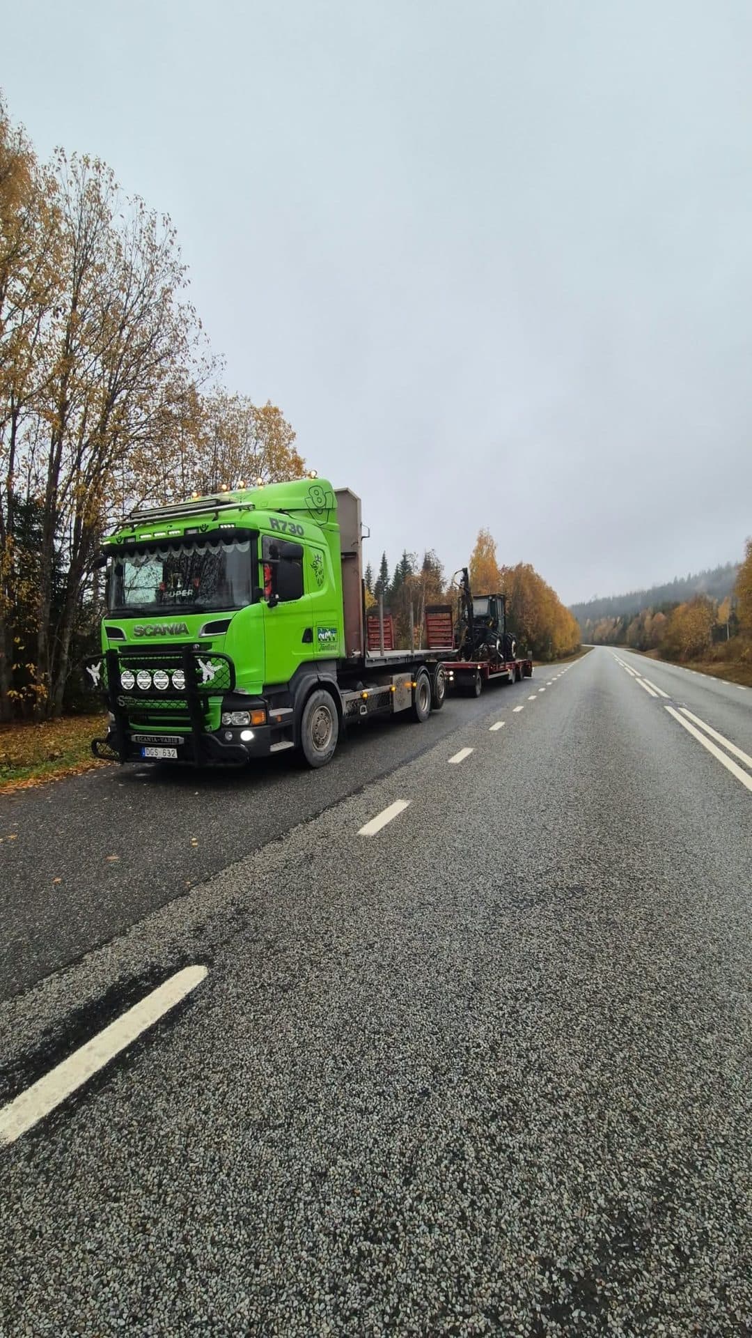 Ekipaget vid vägkanten en höstdag, med gula björkar och skogsklädda berg i bakgrunden